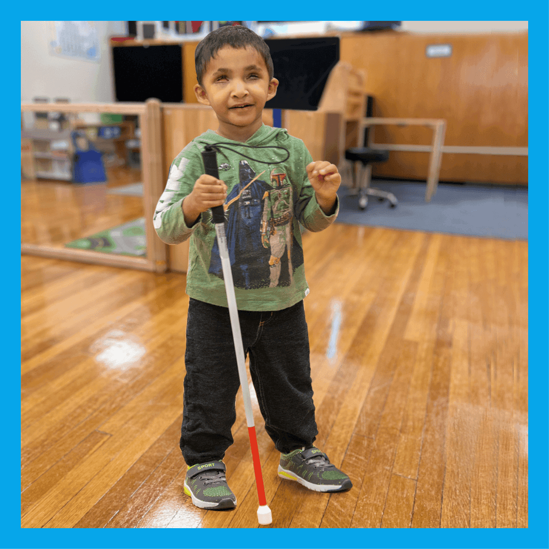 A young student stands with a white cane.