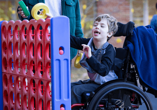 A student in a wheel chair plays with a large Connect Four game.