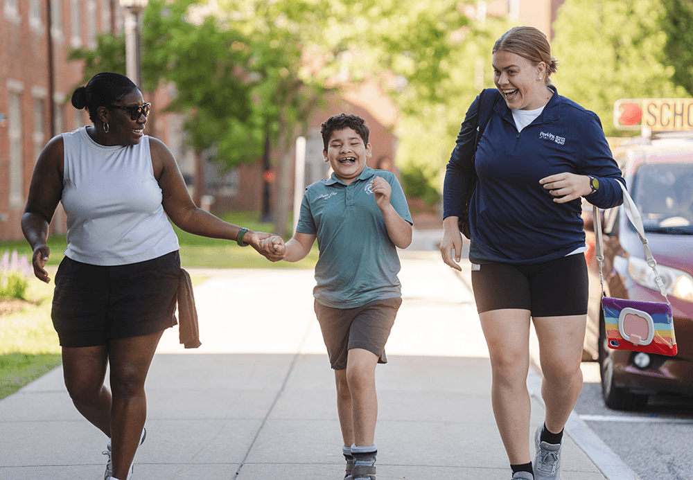 A smiling student walks with happy teachers outside
